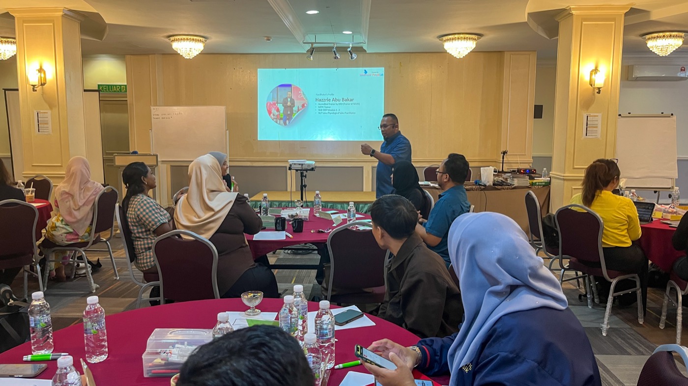 A PeopleLab trainer presenting to a full training hall