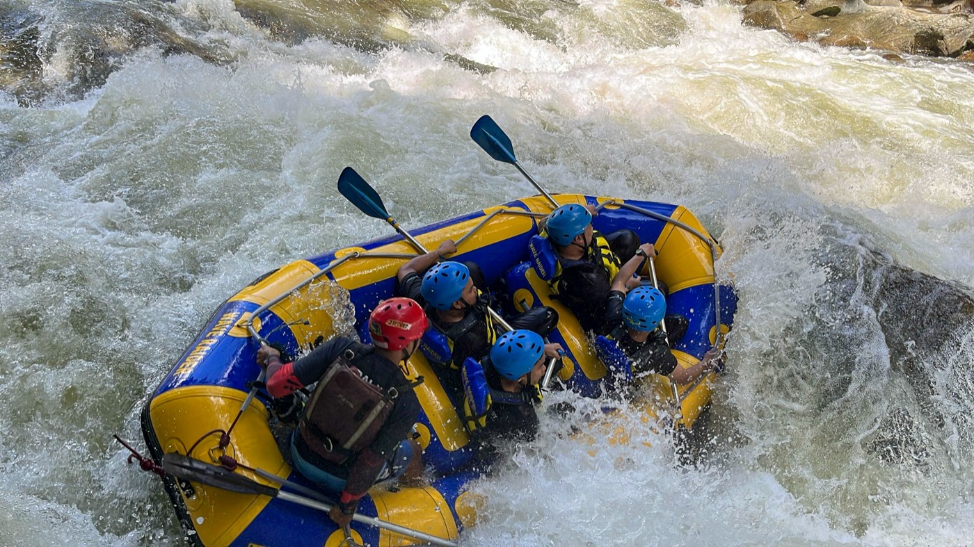 Team paddling through river rapids together