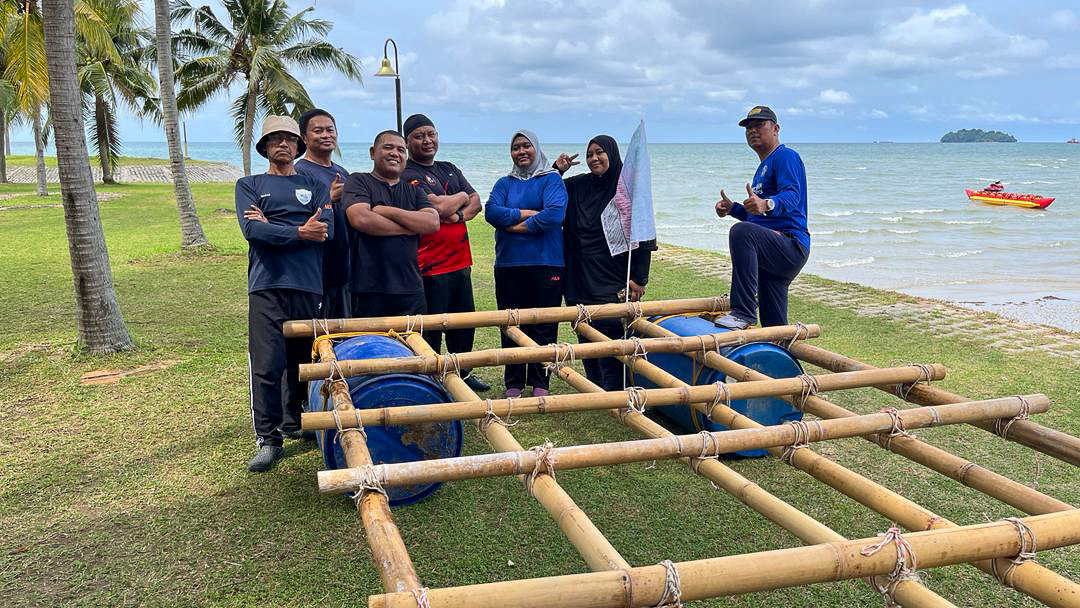 A team building a bamboo raft on the beach