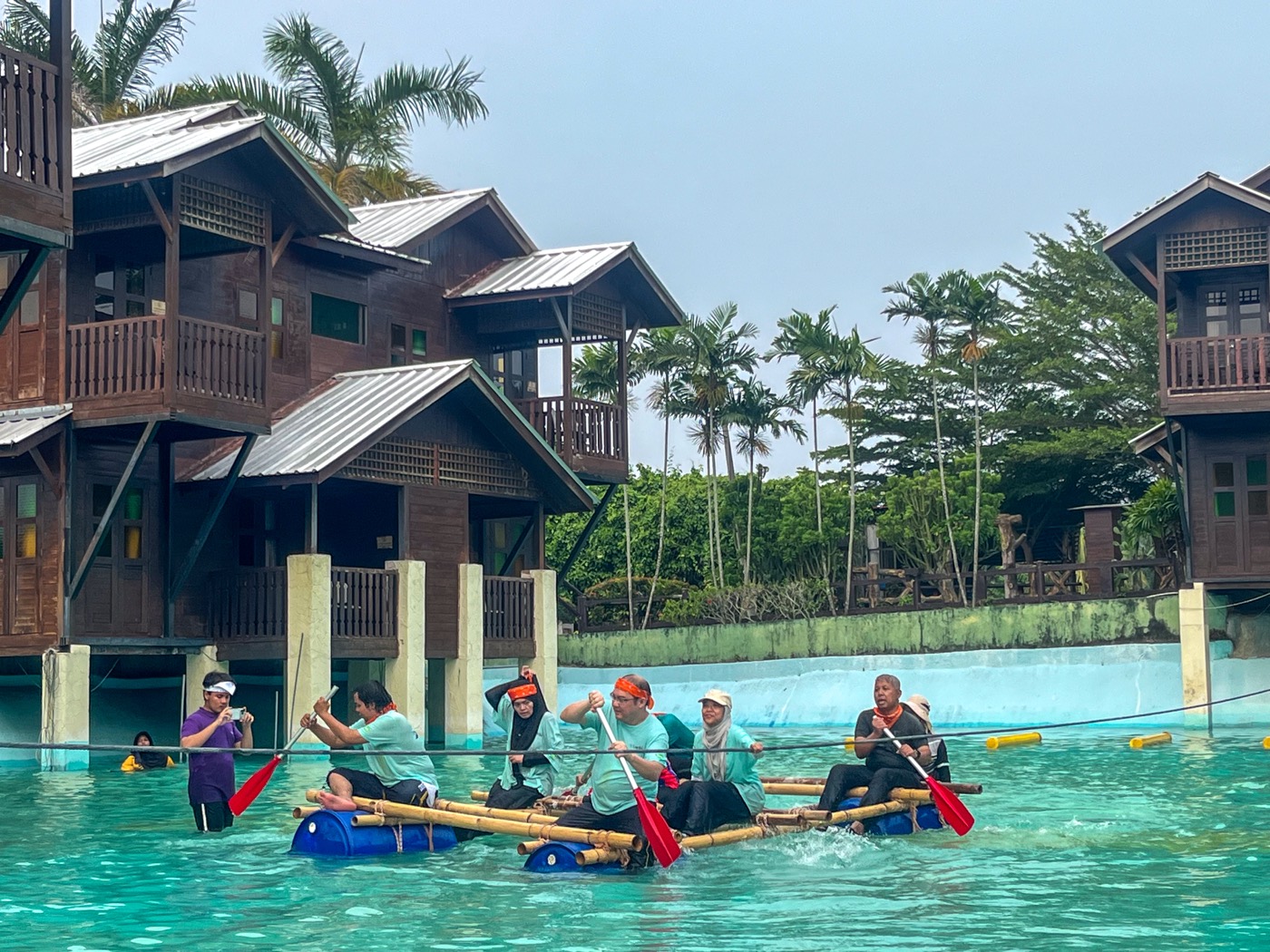Colleagues paddling a bamboo raft at a resort lagoon